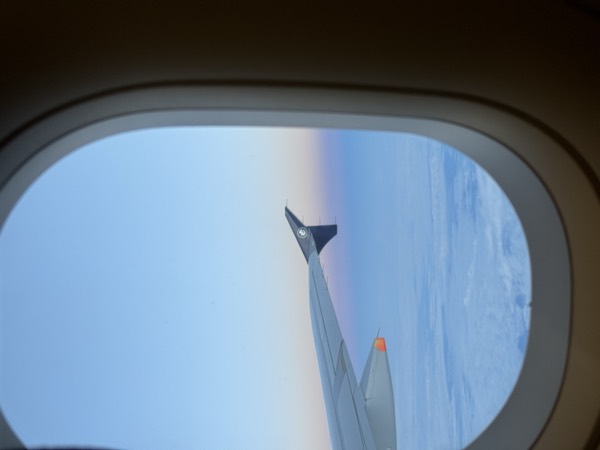 Looking out of an aircraft window at the wing, somewhere above the clouds